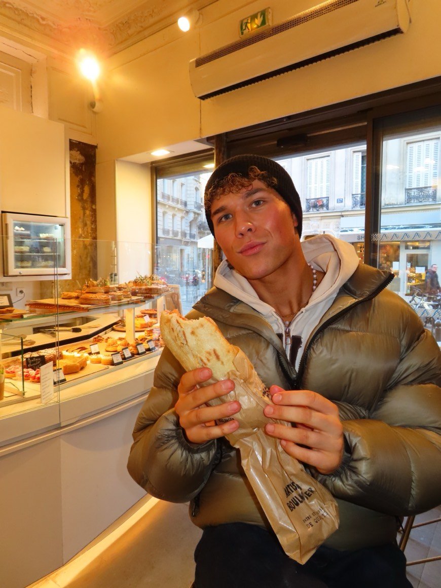 In a bakery, holding a fresh baguette